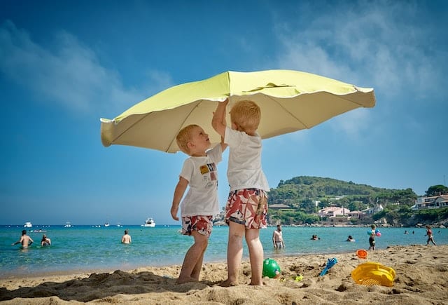 海岸の傘の下で遊ぶ子供達